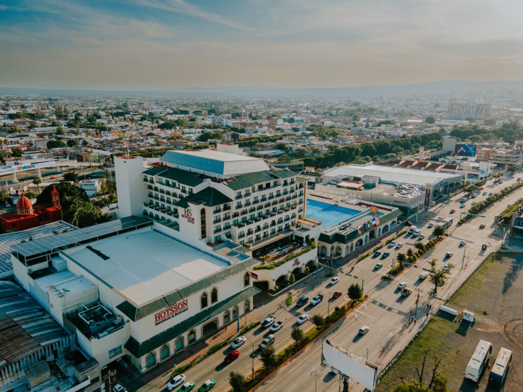 Drone shot capturing a vibrant cityscape with prominent hotel and busy highway.