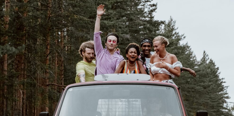 Group of friends having fun on a road trip in a vintage red van.